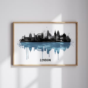 May include: A framed print featuring a black and blue watercolor depiction of the London skyline. The artwork includes iconic landmarks like the London Eye and Big Ben, with the word "LONDON" in white at the bottom.