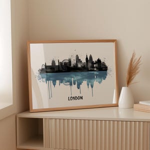 May include: A framed print featuring a black and blue watercolor depiction of the London skyline. The artwork includes iconic landmarks like the London Eye and Big Ben, with the word "LONDON" at the bottom.