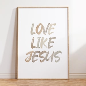 May include: A white framed print with the text "LOVE LIKE JESUS" in a brush script font. The text is in shades of brown and beige.