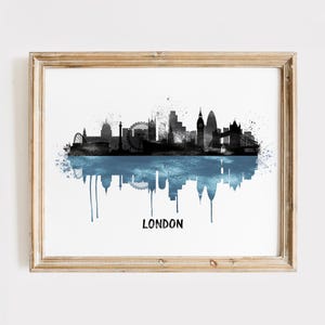 May include: Framed art print featuring a black and blue watercolor depiction of the London skyline. The image includes iconic landmarks and a reflective water effect, with the city name printed below.