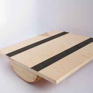 Image of a wooden balance board. The top is made of plywood and is 19 inches square with two strips of grip tape. The rockers are made of reclaimed pine with cork on the bottom to reduce the risk of the board slipping on wood floors.