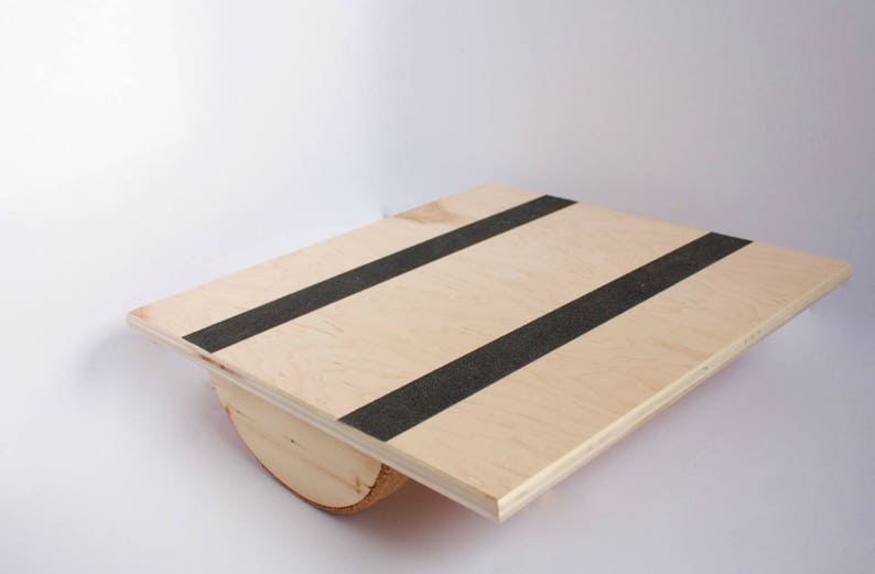 Image of a wooden balance board. The top is made of plywood and is 19 inches square with two strips of grip tape. The rockers are made of reclaimed pine with cork on the bottom to reduce the risk of the board slipping on wood floors.