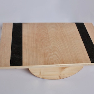 Image of a wooden balance board. The top is made of plywood and is 19 inches by 15 inches with two strips of grip tape. The rockers are made of reclaimed pine with cork on the bottom to reduce the risk of the board slipping on wood floors.