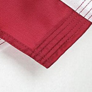May include: Close-up of the hem of a burgundy garment with multiple rows of stitching.