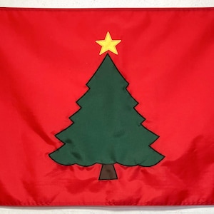 May include: A red flag with a green Christmas tree and a yellow star on top. The tree is outlined in black.