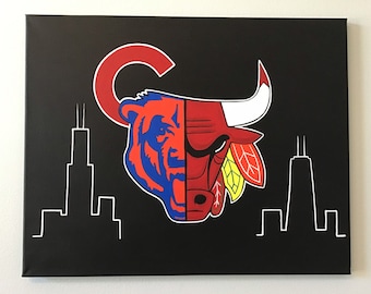 May include: A black canvas painting with a white outline of the Chicago skyline. The center of the painting features a red and black bull head with a white horn and a blue and red bear head. The bull and bear heads are split down the middle, with the bull on the right and the bear on the left. The bull has a yellow and red feather headdress. The bear has a red "C" behind it.