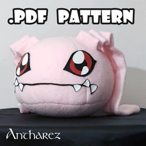 Puede incluir: Un peluche rosa con ojos grandes rojos y negros, dientes blancos y orejas largas. El texto ".PDF PATTERN" está en la parte superior y el nombre "Ancharez" en la inferior. El juguete es probablemente hecho a mano.