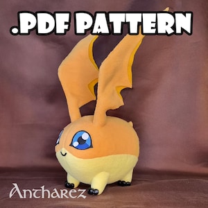 Puede incluir: Un peluche con forma de personaje de dibujos animados, principalmente naranja y amarillo, con grandes ojos azules y orejas en forma de alas. El texto ".PDF PATTERN" está en la parte superior y el nombre "Ancharez" en la parte inferior.