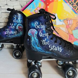 May include: A pair of black roller skates with galaxy-themed designs. One skate says "Dare to Dream" with a jellyfish illustration, and the other says "Born from the Stars" with a jellyfish illustration.