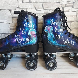 May include: A pair of black roller skates with galaxy-themed designs. One skate features the text "dare to dream" and a jellyfish, while the other skate features the text "Born from the stars" and a jellyfish.