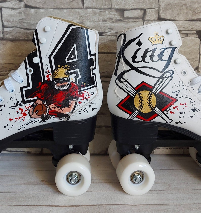 May include: A pair of white roller skates with custom painted designs. One skate features a football player with the number "14" and the other skate features a baseball with bats and the word "King".