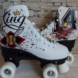 May include: White roller skates with black wheels and black accents. One skate has a baseball design with the word "King" and a crown. The other skate has a football design with the number "4" and a football player.