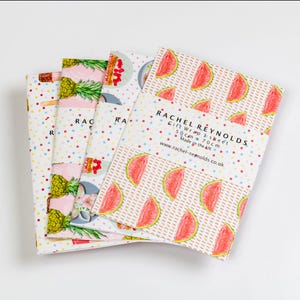 May include: Four sheets of gift wrap with colorful fruit patterns. One sheet features watermelon slices, while others display pineapples and desserts. The gift wrap is from Rachel Reynolds and measures 50 cm x 70 cm.