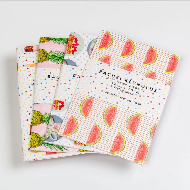 May include: Four sheets of gift wrap with colorful fruit patterns. One sheet features watermelon slices, while others display pineapples and desserts. The gift wrap is from Rachel Reynolds and measures 50 cm x 70 cm.