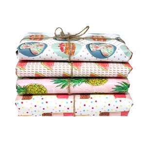 May include: A stack of four wrapped gifts tied with twine. The wrapping paper features colorful patterns including watermelon slices, pineapples, ice cream bars, and floral designs. The gifts are stacked on top of each other against a white background.