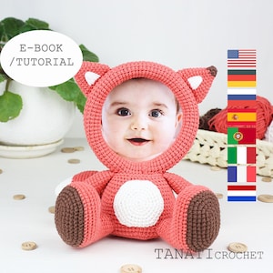 Puede incluir: Marco de fotos de zorro de crochet en rosa y marrón con un círculo blanco en el centro. El marco contiene una foto de un bebé. El texto "E-BOOK / TUTORIAL" está en un círculo blanco en la parte superior de la imagen. El texto "TANATI CROCHET" está en la parte inferior de la imagen.