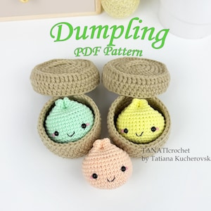 Puede incluir: Tres dumplings de ganchillo con caras sonrientes y mejillas rosadas, dos de los cuales están dentro de pequeñas cestas de ganchillo color canela con tapas. El texto dice Dumpling PDF Pattern y TANATIcrochet by Tatiana Kucherovska.