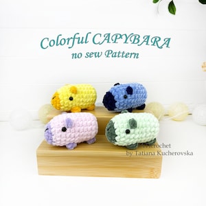 May include: Four plush capybara toys made of soft yarn in yellow, blue, light purple, and light green. Each has small black eyes and a darker snout. The text reads Colorful CAPYBARA no sew Pattern and Crochet by Tatiana Kucherovska.