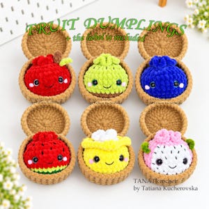 May include: Six crocheted fruit dumplings in brown baskets, including red apple, green lime, blue blueberry, red watermelon, yellow lemon, and pink dragon fruit designs. Each plush features black safety eyes, pink cheeks, and a smiling mouth.