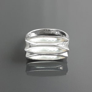 Op de afbeelding: Een zilveren ring met een uniek ontwerp met drie overlappende, gebogen en getextureerde banden.