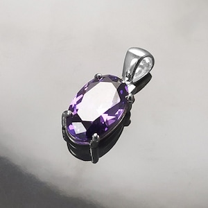 May include: A silver pendant with a large, oval-shaped amethyst gemstone.