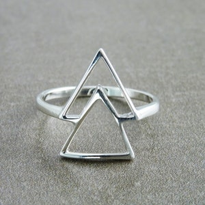 Op de afbeelding: Een zilveren ring met een geometrisch ontwerp met twee overlappende driehoeken.