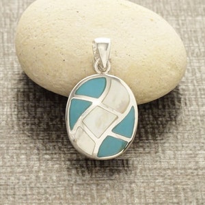 Pode incluir: Um pingente de prata com uma incrustação oval azul e branca. A incrustação é feita de madrepérola e turquesa.