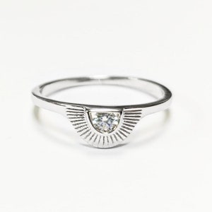 Peut inclure: Une bague en argent avec une petite pierre précieuse transparente sertie dans un motif de soleil.