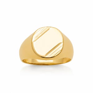 Peut inclure: Une bague chevalière en or poli présentant une face circulaire lisse avec deux rainures diagonales gravées dans les coins supérieur gauche et inférieur droit. L'anneau est en or massif avec une finition brillante et réfléchissante.