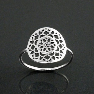 Pode incluir: Um anel de prata com um design delicado e circular que apresenta um padrão de mandala.