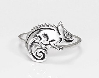 Könnte beinhalten: Ein silberner Ring mit einem detaillierten Chamäleon-Design. Das Chamäleon ist zusammengerollt, mit dem Schwanz um den Körper gewickelt.