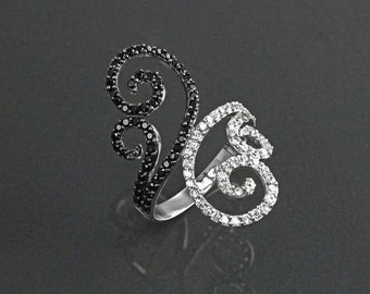 May include: A silver ring with a black and white swirl design. The ring is set with small black and white diamonds.