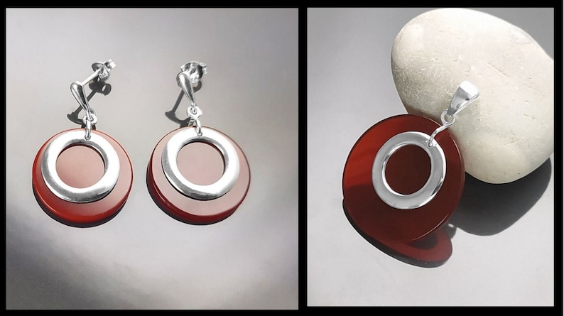 Puede incluir: Un conjunto de pendientes y un colgante de piedra de cornalina roja con detalles plateados. Los pendientes y el colgante presentan un dise&ntilde;o redondo y en capas con un c&iacute;rculo plateado en el centro.