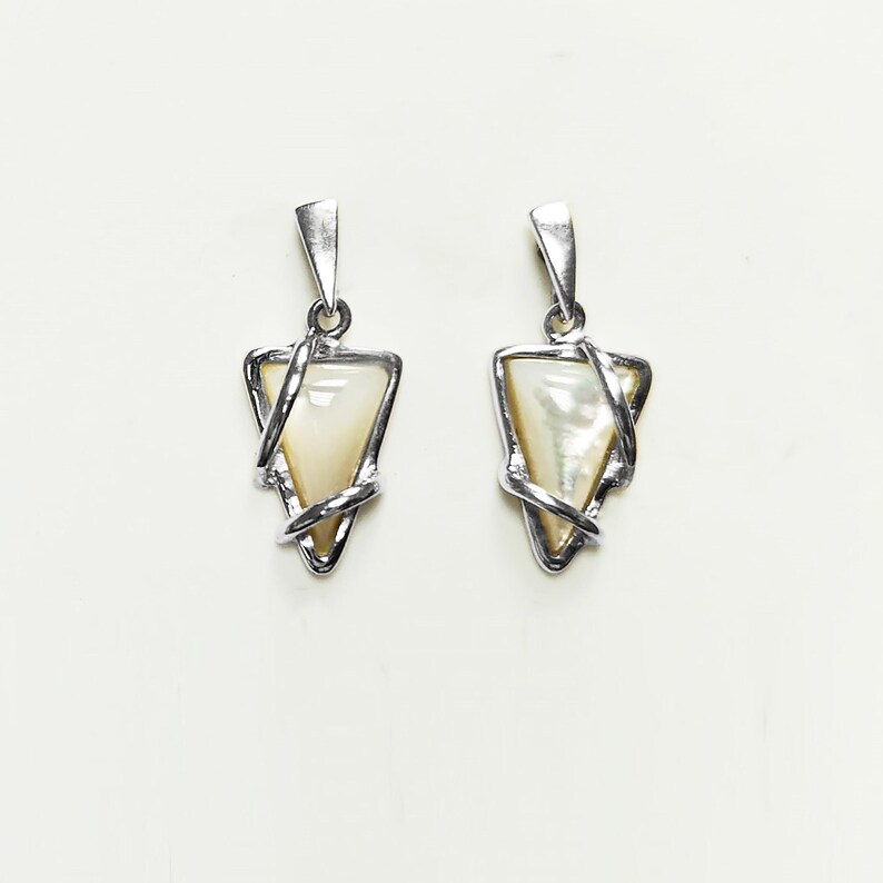 May include: A pair of silver-toned pendants featuring a triangular-shaped iridescent white shell inlay. Each pendant is encased in a polished metal frame that wraps around the edges of the triangle, topped with a simple triangular bail for hanging.