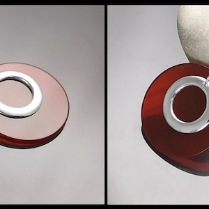 Puede incluir: Un colgante de plata con una piedra de cornalina roja en forma de c&iacute;rculo con un c&iacute;rculo m&aacute;s peque&ntilde;o cortado en el centro.