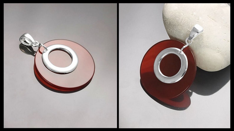 Puede incluir: Un colgante de plata con una piedra de cornalina roja en forma de c&iacute;rculo con un c&iacute;rculo m&aacute;s peque&ntilde;o cortado en el centro.