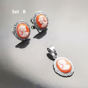 May include: Set B of silver earrings and a pendant necklace. Each piece features a cameo with a white profile of a woman on an orange background.