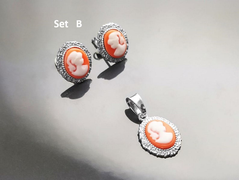May include: Set B of silver earrings and a pendant necklace. Each piece features a cameo with a white profile of a woman on an orange background.