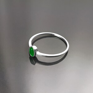 May include: A silver ring with a green oval-shaped gemstone.