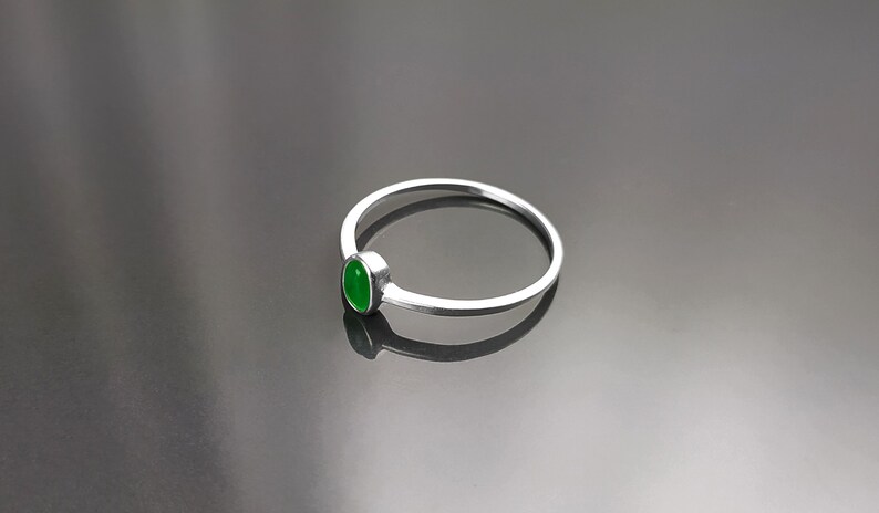 May include: A silver ring with a green oval-shaped gemstone.