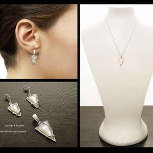 May include: A jewelry set consisting of a pendant necklace and a pair of drop earrings. Each piece features a triangular, iridescent white inlay encased in a silver-toned metal frame. The pendant hangs from a thin chain, and the earrings have posts.