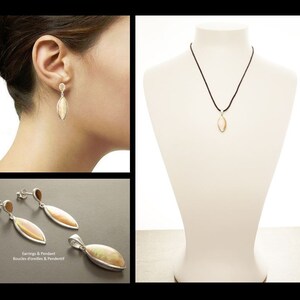 May include: A jewelry set consisting of two drop earrings and a pendant, each featuring a marquise-shaped, iridescent stone set in silver-toned metal. The pendant hangs from a thin black cord, and the earrings have a post-back closure mechanism.