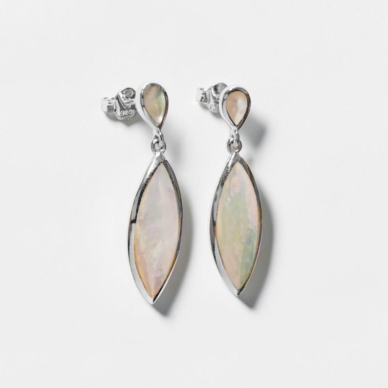May include: A pair of silver drop earrings featuring a marquise-shaped iridescent mother-of-pearl inlay. Each earring consists of a small teardrop-shaped stud connected to a larger, elongated marquise-shaped pendant, both set in polished silver.