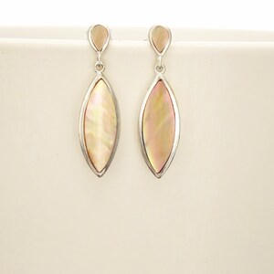 May include: A pair of drop earrings featuring marquise-shaped iridescent shell inlays set in silver-toned metal. Each earring consists of a small teardrop-shaped top piece connected by a jump ring to a larger, elongated marquise-shaped pendant.