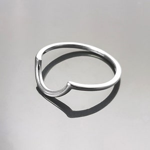 Puede incluir: Un anillo de plata con un diseño abierto único, que se asemeja a una V.