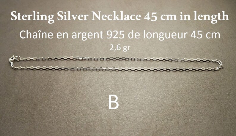 May include: A sterling silver necklace, 45 cm in length, displayed on a gray surface. The necklace is made of small, linked silver pieces. Text on the image reads "Sterling Silver Necklace 45 cm in length" and "2,6 gr".