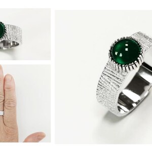 Puede incluir: Un anillo de plata con una banda texturizada y una piedra preciosa redonda verde.