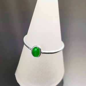 May include: A silver ring with a green oval gemstone.