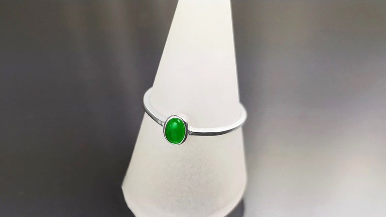 May include: A silver ring with a green oval gemstone.