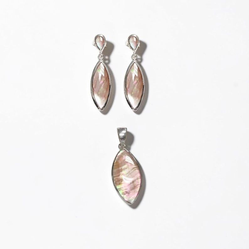 May include: A jewelry set consisting of two drop earrings and one matching pendant. Each piece features a marquise-shaped iridescent shell inlay set in a polished silver-tone metal frame. The shell displays soft pink and white pearlescent tones.